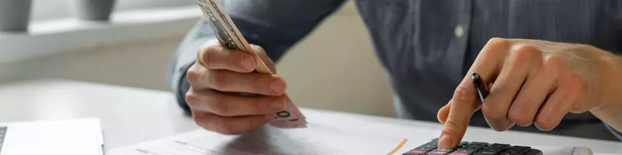 A person using a calculator and looking at bills
