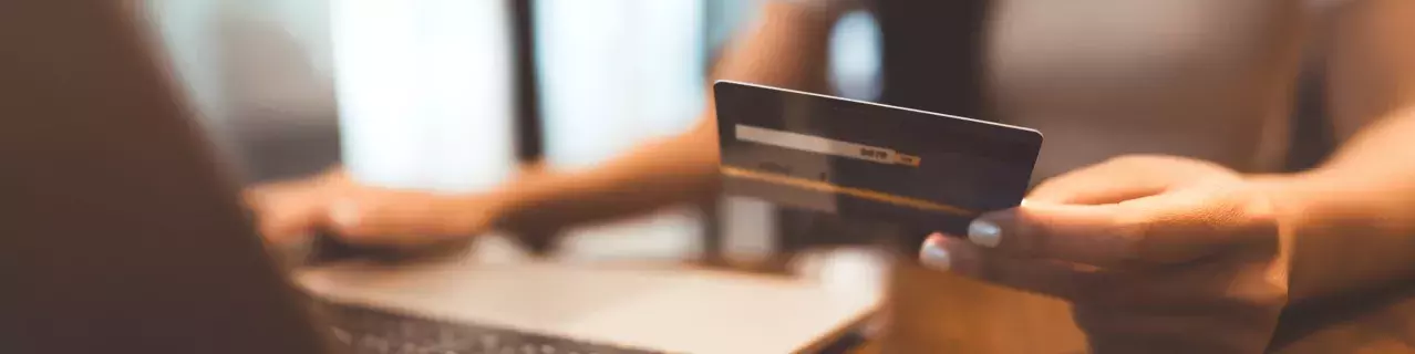 A person working at their laptop holding a credit card