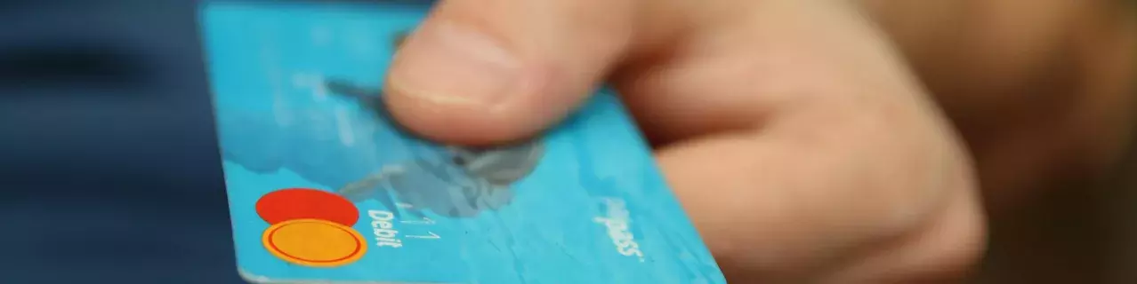 A person holding and offering a debit card for payment