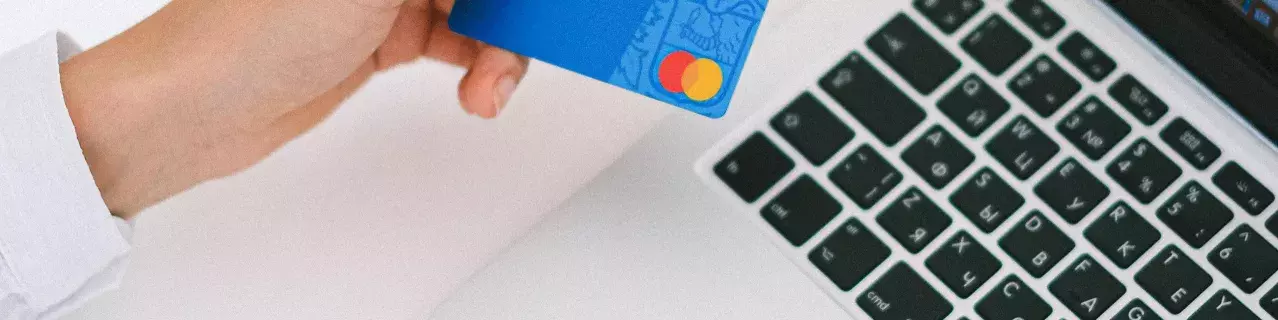 A person looking at their bank card and their laptop.