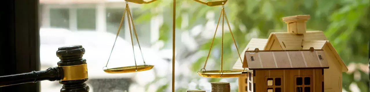 A still art photo of a gavel, house, and scales of justice