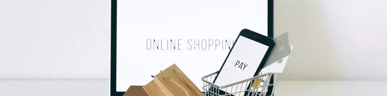 A laptop with a tiny shopping cart, boxes, and a phone