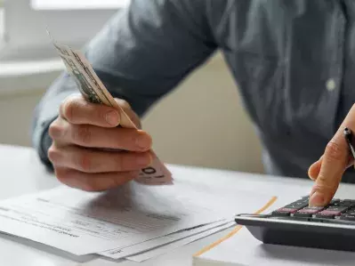 A person using a calculator and looking at bills