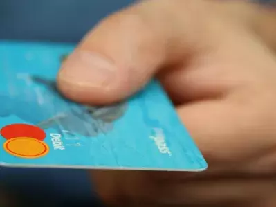 A person holding and offering a debit card for payment