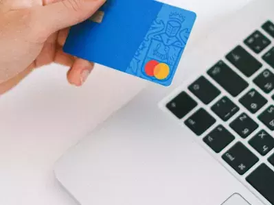 A person looking at their bank card and their laptop.
