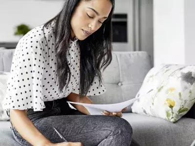 A person on their couch working on bills