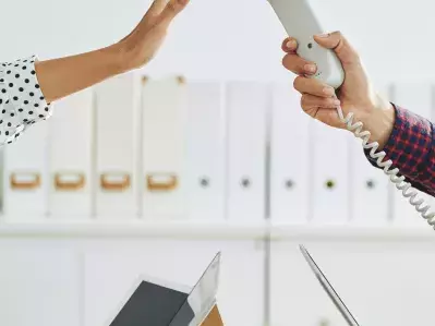 A person holding up a hand to a phone, indicating they don't want to take a call