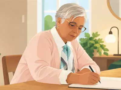 Man writing in notebook at dining table