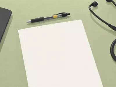 Stethoscope with pen and paper beside laptop
