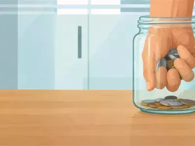Hand putting coins into a glass jar