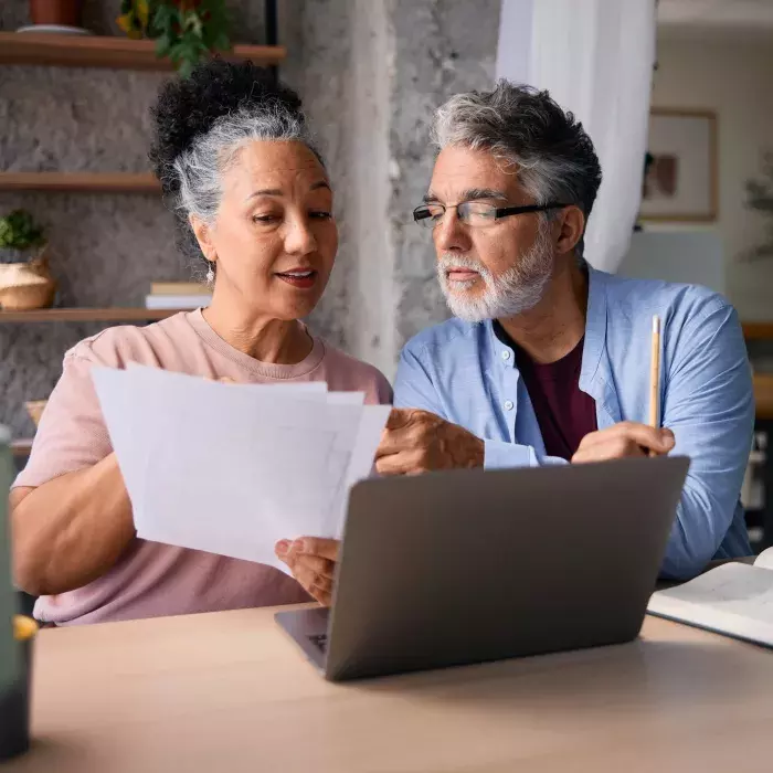 A photo of a couple sitting at a computer, working on their debts.